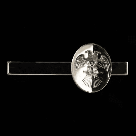 Dagas y espadas masónicas exhibidas en un soporte de madera tallada. Dije de oro con estrella masónica de cinco puntas sobre fondo oscuro. Espadas masónicas con empuñadura ornamentada y símbolos grabados. Colección de dijes de oro con emblemas masónicos, incluida la estrella masónica. Detalle de una daga masónica con símbolos del Rito Escocés en la hoja.